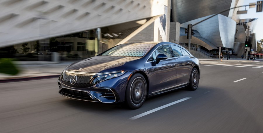 Auto eléctrico Mercedes-Benz en carretera a velocidad con edificios de fondo