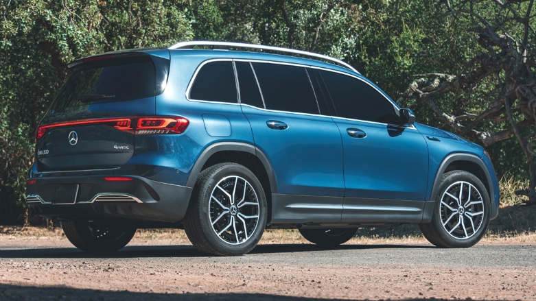 Vista trasera de Camioneta Mercedes Benz EQB familiar color azul estacionada sobre terreno rocoso.