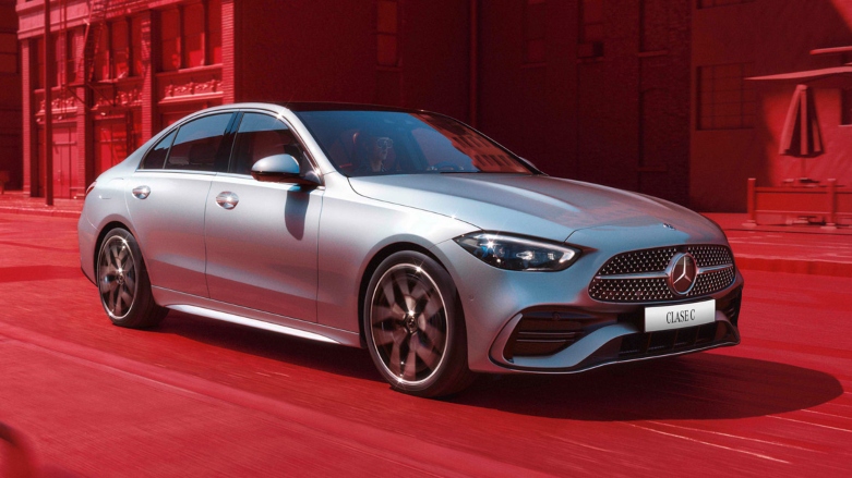 Vista frontal izquierda de Auto Sedan Mercedes-Benz Clase C color gris conducido por calles de la ciudad con tinte rojo.