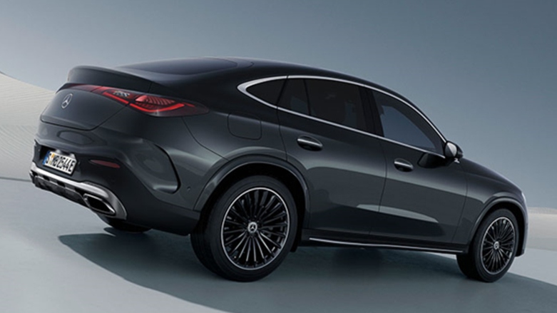 Vista trasera derecha de Mercedes-Benz GLC Coupé color negro siendo conducido sobre desierto blanco.